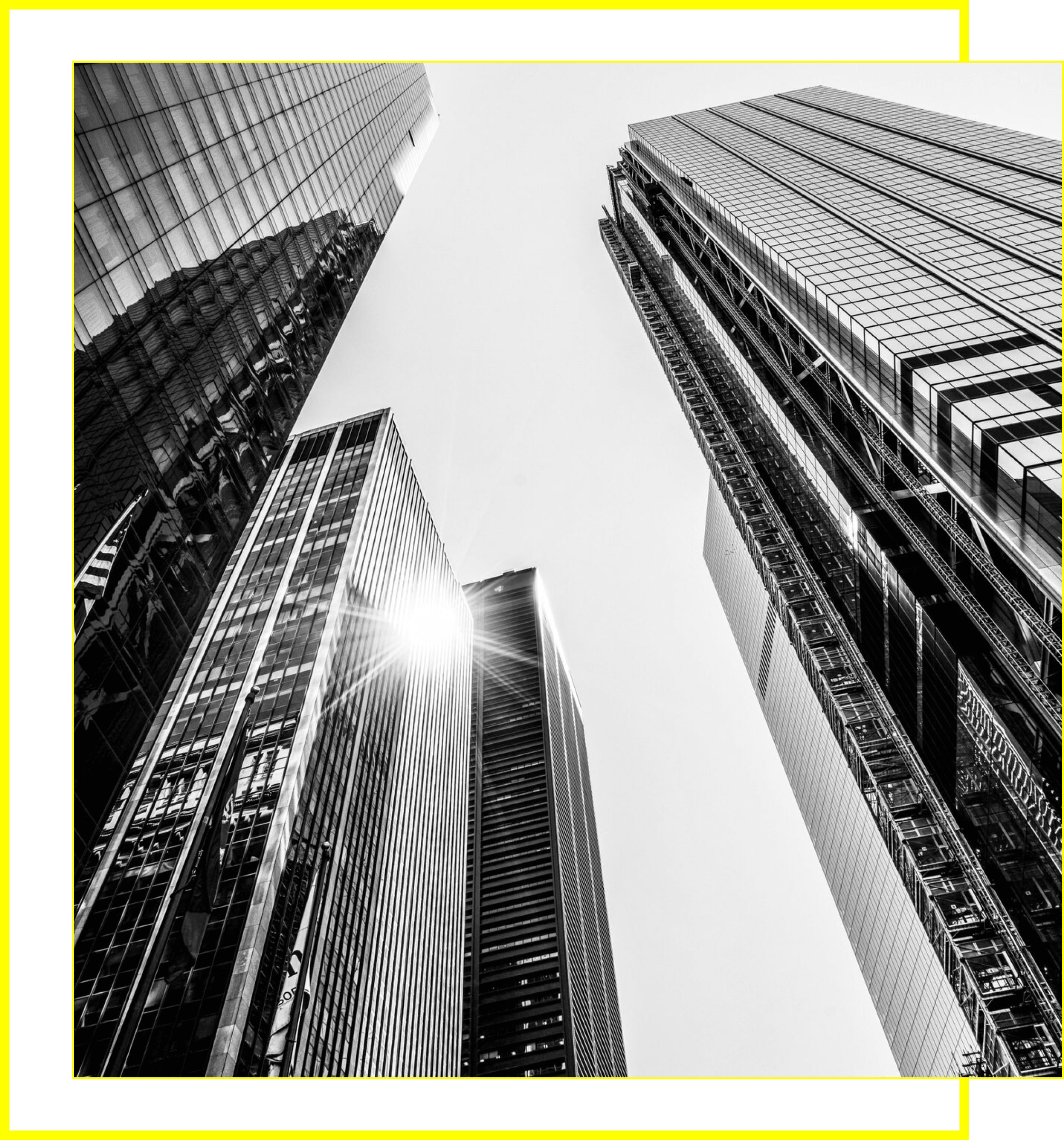 Black and white photo of skyscrapers from below with sunlight reflecting